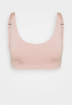 Lichtroze naadloze beha met brede banden, een ronde halslijn en verstelbare hardwaredetails. Gemaakt van een zachte, rekbare stof.