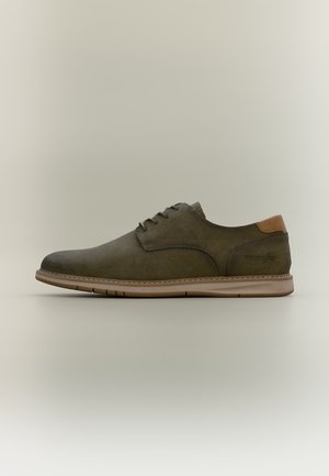 Chaussure décontractée en cuir vert foncé à lacets avec semelle et talon marron clair, présentée en profil sur fond neutre.