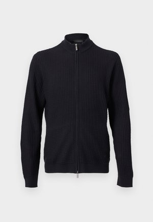 Maglione nero lavorato a maglia con cerniera frontale completa e collo alto, polsini e orlo a coste, mostrato su uno sfondo neutro.