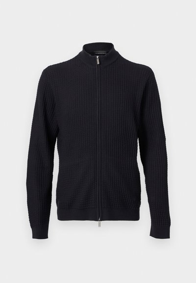 Μαύρο πλεκτό πουλόβερ με υφή, πλήρης φερμουάρ μπροστά και ριμπ γιακάς, μανσέτες και τελείωμα, παρουσιάζεται σε ουδέτερο φόντο.