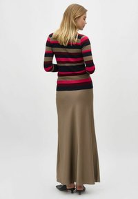 Maglia a maniche lunghe a righe nei colori blu navy, rosso e beige. Abbinata a una gonna maxi color khaki. La gonna presenta una texture liscia e una leggera apertura.