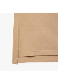 Beige kangas na mwelekeo wa muundo wa nyuzi. Inahem kulingana na upinde safi, na kushona kidogo kwenye ukingo.