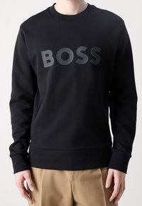 Felpa nera con scollo rotondo, caratterizzata da un logo "BOSS" lucido al centro. Tessuto morbido e polsini e orlo a coste.