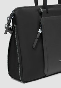 Bolso sintético negro con textura suave, forma estructurada, cierre con cremallera y detalles de herrajes en tono plateado.