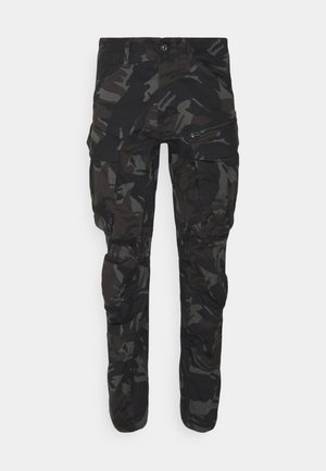 Cargo pants in a black camo pattern, featuring multiple pockets, a zippered side pocket, and a fitted design. Made from durable fabric.