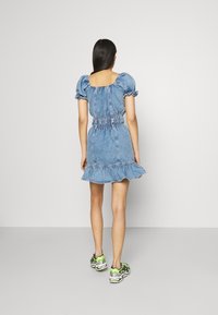 Denim-mekko, jossa on lyhyet puff-hihat, joustava vyötärö ja röyhelöhelma. Yhdistetty vihreisiin ja mustiin urheilukenkien kanssa.