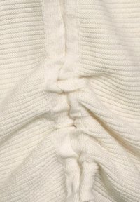 Tessuto bianco lavorato a maglia con texture a coste, caratterizzato da accenti arricciati lungo la cucitura, creando un effetto drappeggiato. Materiale morbido e elasticizzato.