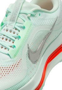 Nike Pegasus running shoe in light mint green with a mesh upper, reflective silver swoosh, and an exposed orange air sole.