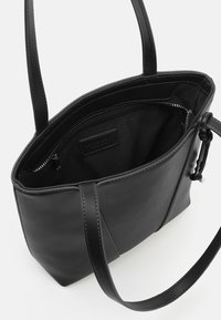 Borsa tote in pelle nera con una texture liscia, dotata di una tasca interna con cerniera e lunghi manici piatti per il trasporto.