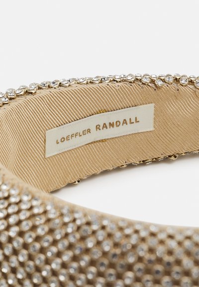 Un bandeau en tissu doré présentant une surface texturée avec des strass transparents le long du bord. L'étiquette indique "Loeffler Randall."