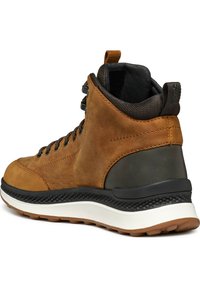 Bota de senderismo de cuero marrón con una suela de goma texturada, talón oscuro en contraste, ojetes de metal y cordones marrones. Diseño de altura a la altura del tobillo.