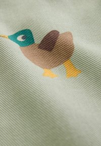 Simplified cartoon mallard duck with green head, brown body, dark brown wing, and yellow feet printed on textured light fabric.