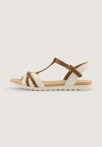 Braun-weiße Sandale mit T-Riemen-Design, weichem Stoff und Lederakzenten, strukturiertem Sohlen und einer seitlichen Schnalle zur Anpassung.