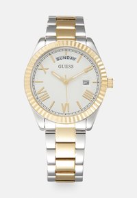 Silver and gold metal watch with a white face, Roman numerals, and a date display, featuring a textured bezel and a link bracelet.