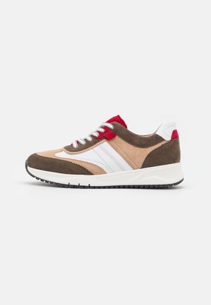 Zapatilla baja en ante beige, marrón, blanco y rojo con cordones blancos y suela de goma negra, vista de perfil.