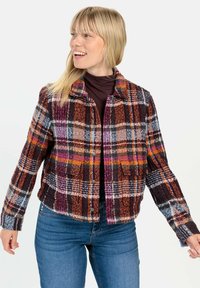Karierte Jacke aus mehrfarbigem Stoff mit einem Kragen, Knopfleiste und zwei Brusttaschen. Weicher Stoff mit auffälligen orangefarbenen, lila und blauen Mustern.
