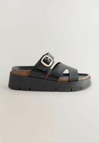 Sandalo in pelle nera con due larghe cinghie, una fibbia dorata, sottopiede in sughero e suola esterna in gomma nera spessa con dettagli a scanalature.