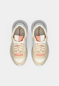 Beige running shoes with a light blue accent, featuring a soft pink tongue and laces, textured rubber sole, and suede detailing.