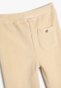 Beżowe legginsy z kordurowego materiału o prążkowanej fakturze, z małą tylną kieszonką i detalem w postaci guzika. Miękka tkanina i elastyczny pas.
