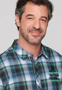 Camicia a maniche corte a quadri in blu navy, verde e bianco. Presenta un colletto con bottoni, logo ricamato e dettagliata con strisce a contrasto.