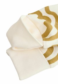 White fabric cap with a soft texture, featuring gold wavy patterns. The design includes folded cuffs for added detail.