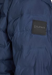 Giacca puffer navy con finitura testurizzata, caratterizzata da un distintivo etichetta in gomma nera con la scritta "CALAMAR" sul braccio sinistro.