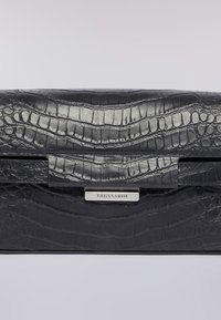 Svart läderkuvert med krokodilsmönster, med ett texturerat lock och metallisk lås med varumärket "Trussardi" på en silverplatta.