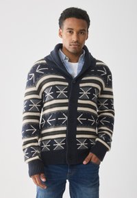 Navy- und Cremefarbener Cardigan mit einem Pfeilmuster, ausgestattet mit einem Schalkragen, Knöpfen und gerippten Bündchen, aus Strickstoff gefertigt.