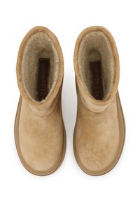 Botine ancle din suede bej, cu o căptușeală moale din fleece de culoare crem și o talpă din cauciuc. Prezintă accente cusute și un design plat.