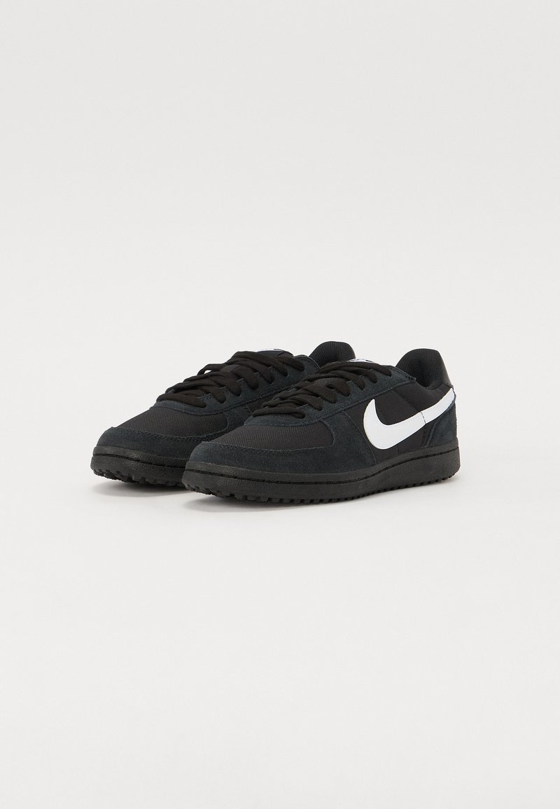 Czarne sneakersy wykonane z zamszu i siateczki z białym logo Nike. Zawierają sznurówki, gumową podeszwę i okrągły kształt noska.
