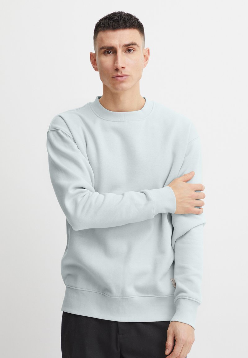 Lichtblauwe sweatshirt van zachte stof, met een ronde hals, ribgebreide manchetten en een klein label aan de onderlinkerkant.