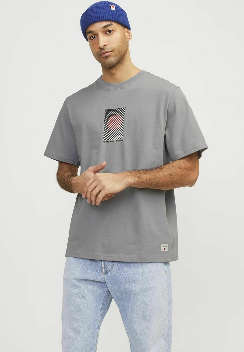 Grijze katoenen t-shirt met een geometrische grafiek in rood, zwart en wit, met korte mouwen en een klein logo-label aan de zoom.