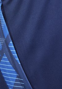 Marineblaues Gewebe mit einer glatten Textur zeigt blaue geometrische Muster und Streifen. Eine sichtbare Naht verläuft entlang der Kante.