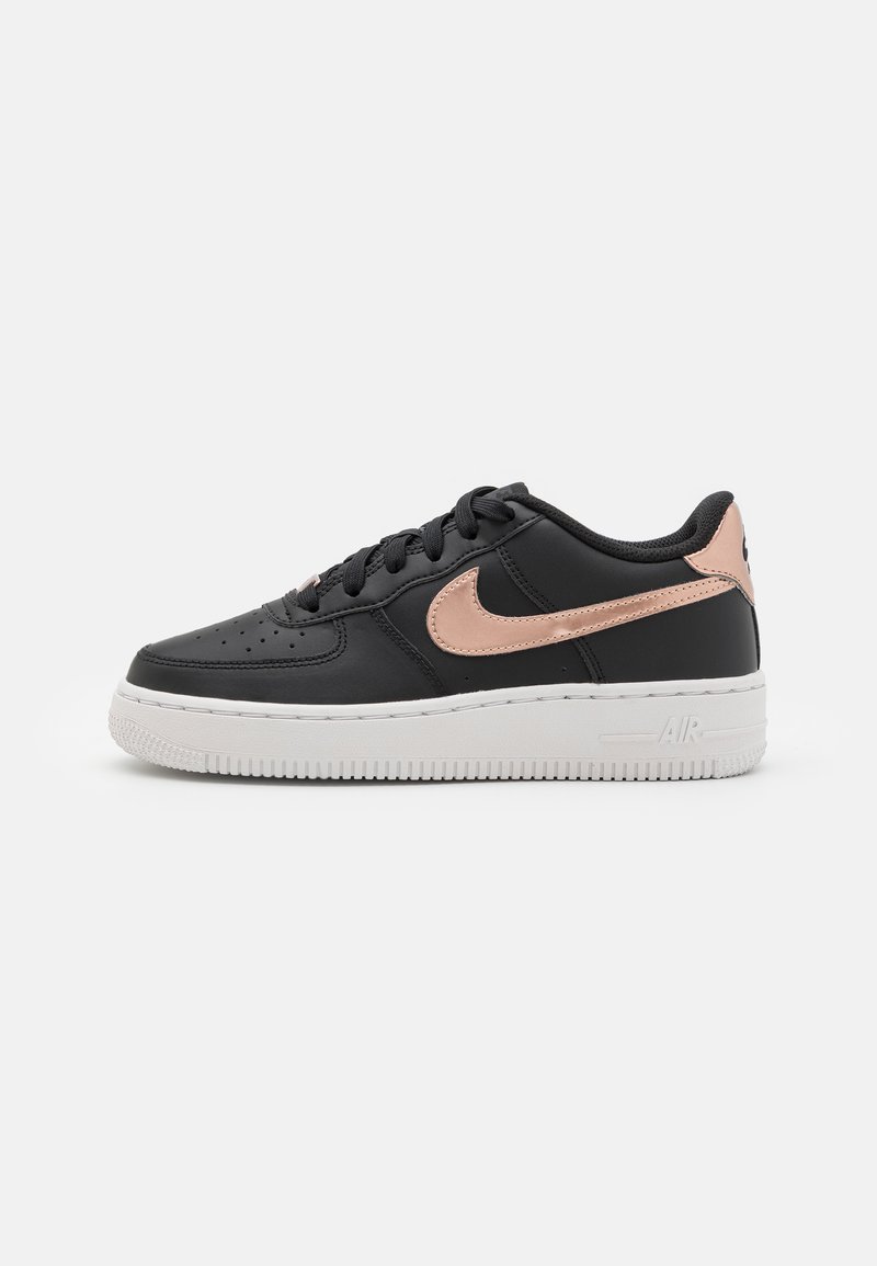 Crne kožne tene s metalik ružičasto zlatnim Nike swooshom, bijelim gumenim potplatom, okruglim vrhom i teksturiranim detaljima na gornjem dijelu.