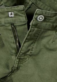 Gröna bomullsbyxor med dragkedja, knappstängning och kontrasterande sömmar. Slät textur med en figursydd design.