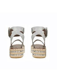 Sandalias de espadrille de cuero plateado con suela de yute trenzado, tacón apilado y acentos de tachuelas metálicas en la plantilla.