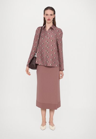 Rosa bluse med geometriske mønstre, pares med et matchende midi-skjørt. Glatt stoff, avslappet passform og lave hæler med spiss tå.