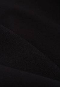 Svart tyg med en slät textur, som visar en lätt lyster och subtil vävstruktur, arrangerat i mjuka veck.