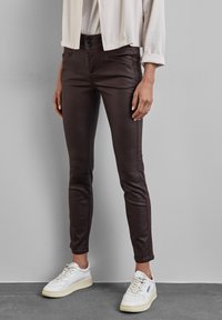 Bruna, slim-fit byxor med en mjuk textur, utrustade med två framfickor och stängning med två knappar. Matchade med vita sneakers.