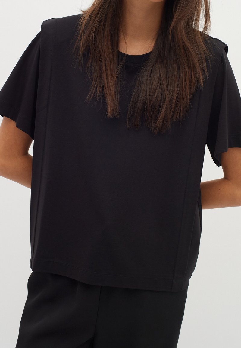 Svart kortärmad t-shirt i mjuk bomull, med en lös passform och enkel rund halsringning. Minimalistisk design utan synliga mönster.