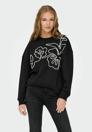 Zwarte sweatshirt met witte bloemomtrekken, ronde hals en lange mouwen, gecombineerd met zwarte jeans. Soepele textuur met een relaxte pasvorm.