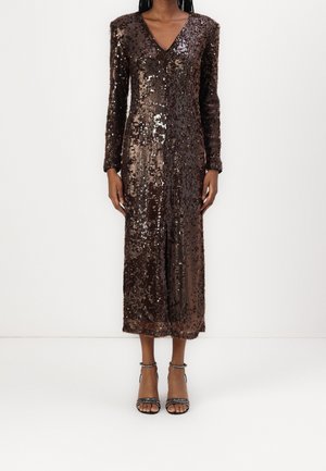 Person wearing a long-sleeve, dark brown sequined midi dress with a V-neckline and front slit, paired with black ankle-strap heels.