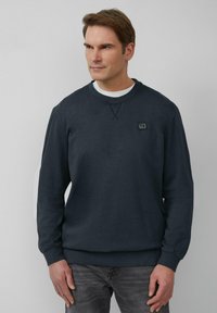 Donkerblauwe sweatshirt met een ronde hals, textuurstof en een logo-opdruk op de borst. Lange mouwen en ribgebreide manchetten en onderkant.