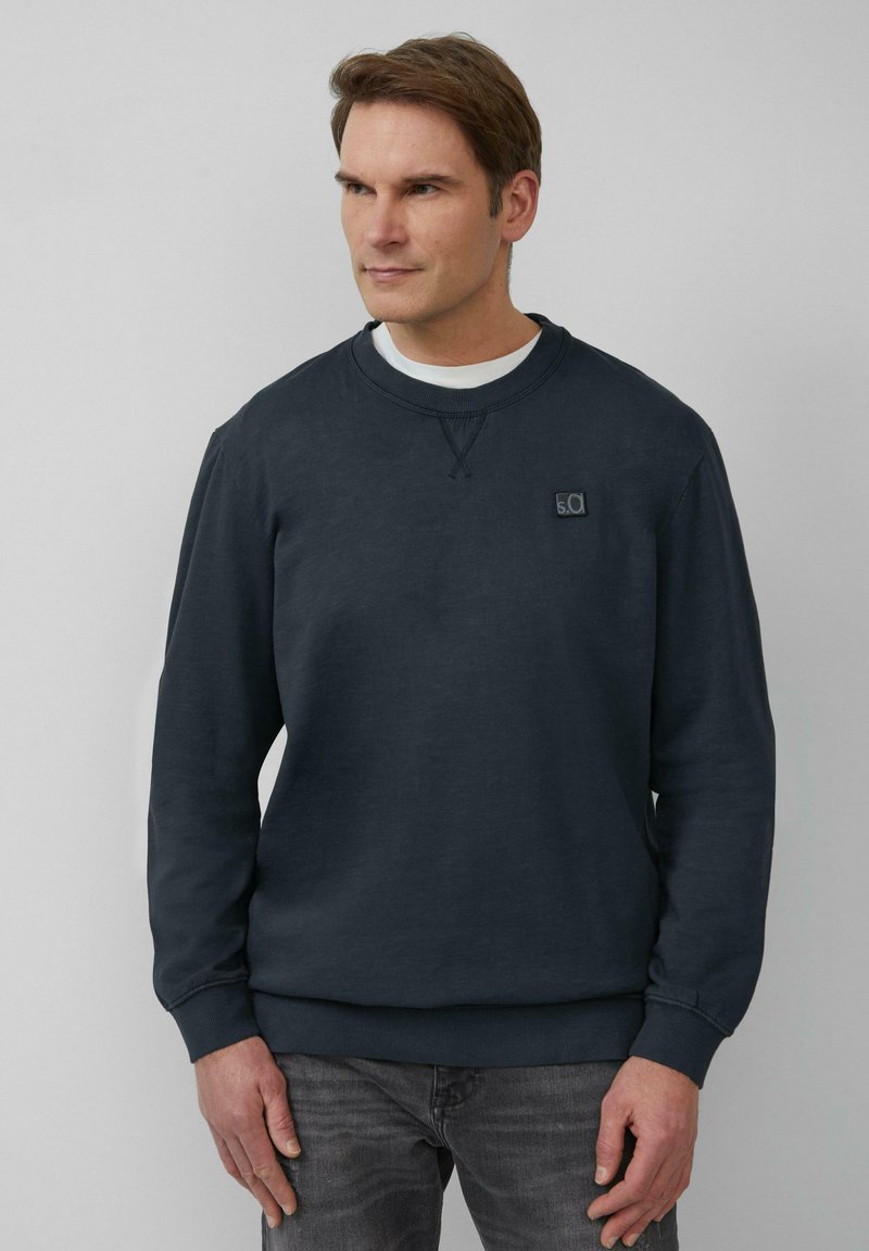 Donkerblauwe sweatshirt met een ronde hals, textuurstof en een logo-opdruk op de borst. Lange mouwen en ribgebreide manchetten en onderkant.