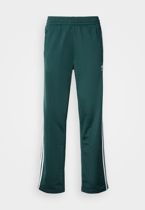 Dark green athletic pants with a textured fabric, elastic waistband, and white side stripes. Logo printed near the upper left front.