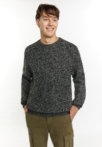 Pulover tricotat în tonuri de negru și alb, cu guler rotund, mâneci lungi și tiv côtat, asortat cu pantaloni cargo kaki.