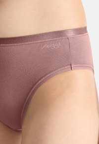 Sous-vêtement en mélange de coton rose clair avec une texture lisse, coupe taille basse et un logo discret près de la ceinture. Ceinture élastique réglable.