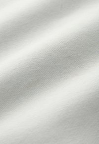 Puha fehér textil, sima és enyhén textúrázott felülettel, finom, egységes szövési mintákkal.