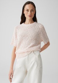 Maglione a maniche corte lavorato a maglia di un rosa chiaro, con una vestibilità morbida e testurizzata, orlo a costine, abbinato a pantaloni bianchi a vita alta.