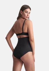 Costume da bagno intero nero con spalline regolabili, vita alta e design con schiena a taglio. Realizzato in materiale liscio e elastico.